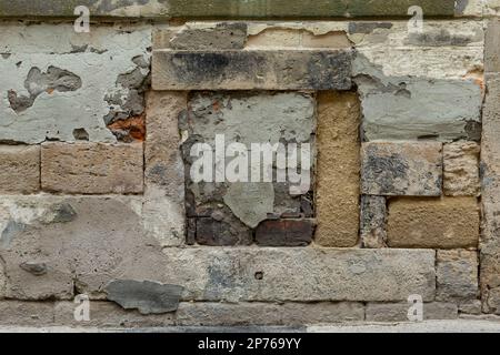 Grunge and Weathered Textured Old Exterior Wall Built with Sandstone Blocks, Covered with Peeling Plaster Stock Photo