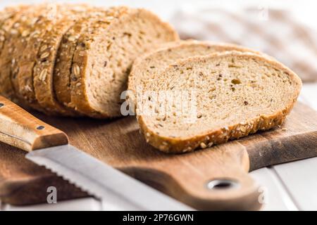 Sliced whole grain bread. Tasty wholegrain pastry with seeds on the cutting board. Stock Photo