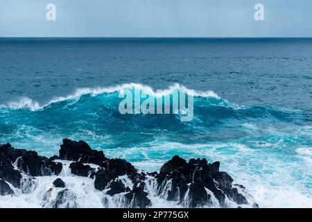 Waves hitting some rocks and creating big water columns Stock Photo