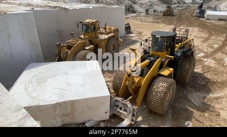 Wheel loaders working at a huge marble quarry in Europe. Transporting the marble blocks. Stock Photo