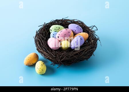 Colorful Easter eggs inside a nest on blue background Stock Photo