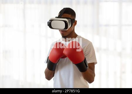 Athletic young black man in VR glasses and boxing gloves Stock Photo