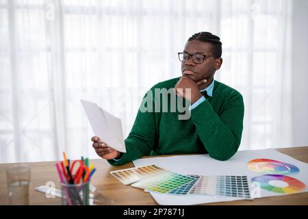 Black Designer Man Holding Palette Thinking Choosing Color At Workplace Stock Photo