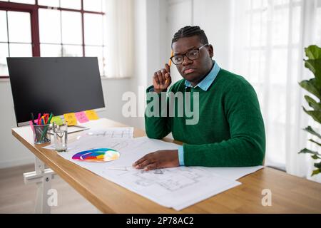 Thoughtful Black Engineer Man Working On Technical Drawing At Workplace Stock Photo
