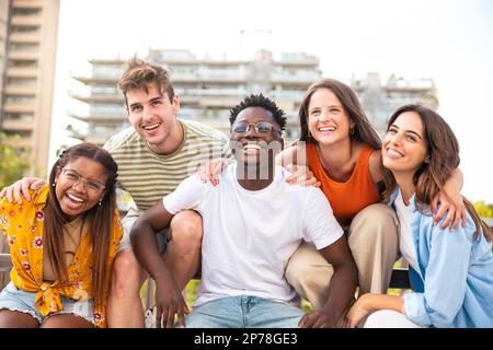 Group of five multiracial friends laughing and having fun outdoors - Cheerful young people laughing together at city - Friendship concept. Stock Photo