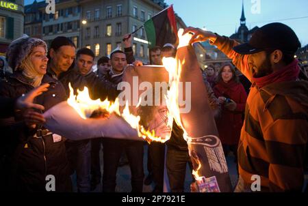 Protestors burn a photo of Libyan Leader Moammar Gadhafi, during a rally organized by Amnesty International Switzerland in solidarity with the Libyan opposition and against Moammar Gadhafi's crackdown on peaceful protesters in Libya, on the federal square in Bern, Switzerland, Wednesday, Feb. 23, 2011. (AP Photo/Keystone/Marcel Bieri)
