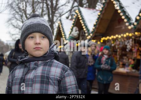 The young boy looked sad at the Christmas market Stock Photo