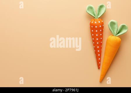 Toy carrots with bunny ears on beige background. Easter holiday concept. Stock Photo