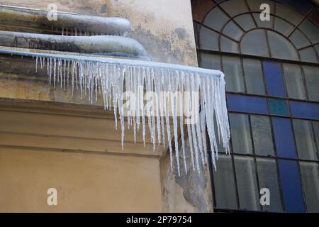 Dangerous icicles hanging from the roof in winter Stock Photo