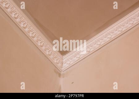 Installation of ceiling moldings. Worker fixes the plastic molding to the ceiling. Stock Photo