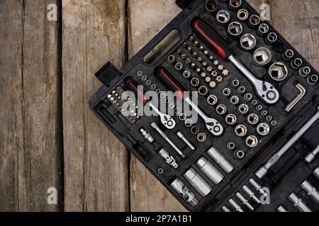Black tools box on the wooden board. Wooden background. Set of wrenches and bits. Stock Photo