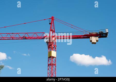 Big red metal construction crane set against blue sky low angle view. Stock Photo