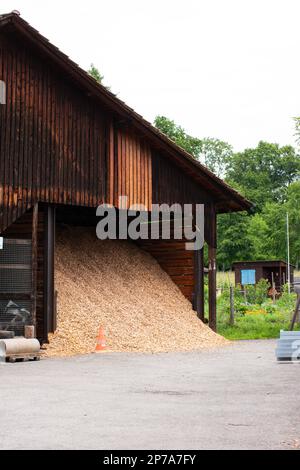 Big pile of saw dust wood shavings overflowing from an outside wood processing site's barn no people. Stock Photo