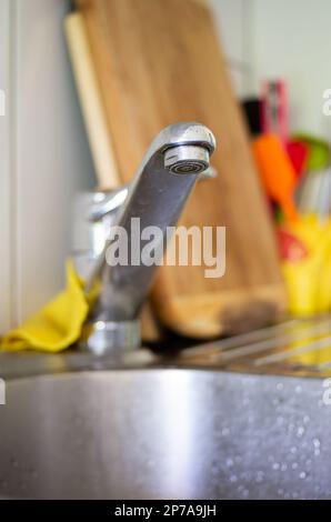 Kitchen sink faucet close up shot shallow depth of field wooden board in the background. Stock Photo