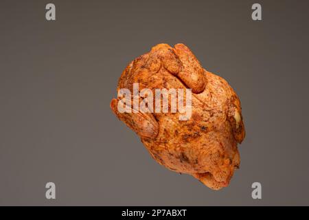 Fresh whole chicken, raw and ready seasoned. Close up studio shot, isolated on brown background. Stock Photo