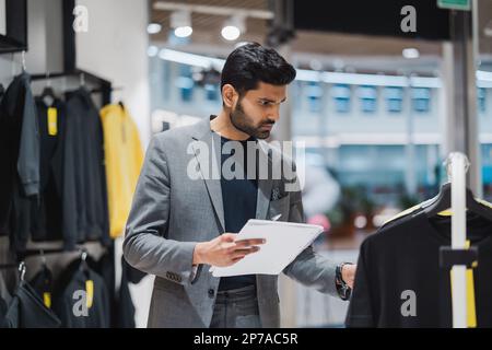 Young man working in clothing store Stock Photo
