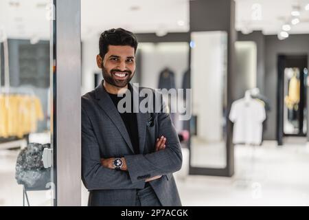 Smiling owner standing at doorway of clothing store Stock Photo