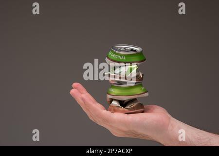 Caucasian male holding two crushed tin metal beer cans. Close up studio shot, isolated on brown background. Stock Photo