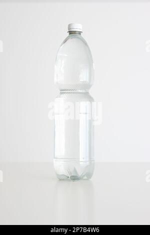 Large clear plastic water bottle with close white cap. Vertical studio shot, isolated on white, no people. Stock Photo
