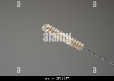 Bottle cleaning brush. Metal woven handle plastic brush, close up studio shot, isolated on gray background. Stock Photo