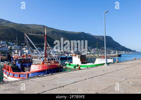 Fishing boats moored in Kalk Bay Harbour, Cape Town, Western Cape, South Africa at sunset, Kalk Bay and St James are visible beyond Stock Photo