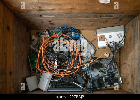 Electronic electric device waste collecting large wooden bin. Contains various defective or obsolete devices collected to be recycled. Top view, no pe Stock Photo
