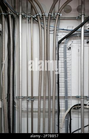 Vertical wall mounted pipes and electrical cables in an industrial ...