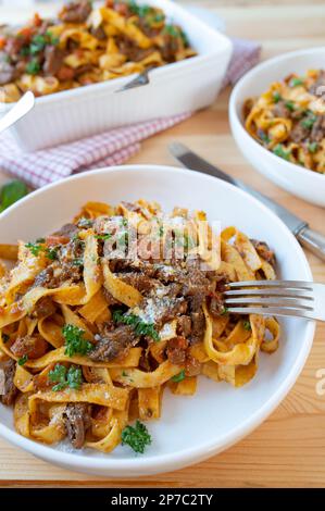 Pasta with stewed beef an vegetables on plates on kitchen table background Stock Photo
