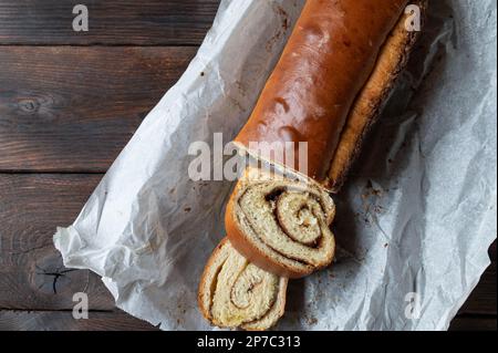 Loaf of yeast cake with cinnamon roll filling isolated on dark wooden table. Flat lay Stock Photo