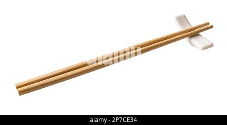 Wooden chopsticks on a white chopstick rest cutout. Pair of bamboo chopsticks on porcelain holder  isolated on a white background. Full depth of field Stock Photo