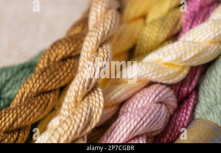 Multi-colored sewing threads for embroidery with selective focus, twisted into bundles. Hobby, handmade, embroidery Stock Photo