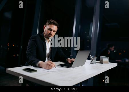 young practitioner on the robot to make notes. The male works in the evening in the office Stock Photo