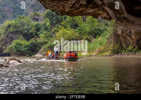 Tourist canoes entering a cave tunnel on a river in Ninh Binh, Vietnam. Stock Photo