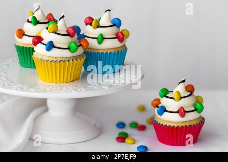 Cakestand with Christmas cupcakes decorated with strings of colorful candy Christmas lights Stock Photo