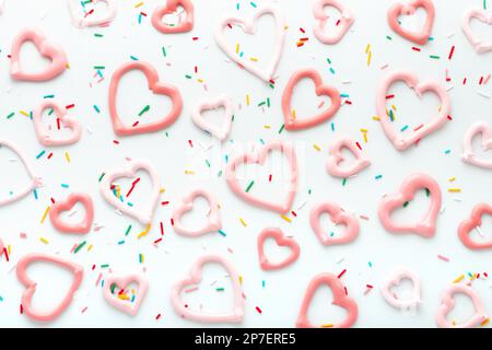 sweet meringue kiss cookies of heart shapes and sprinklers on white background, concept of St. Valentines Day Stock Photo
