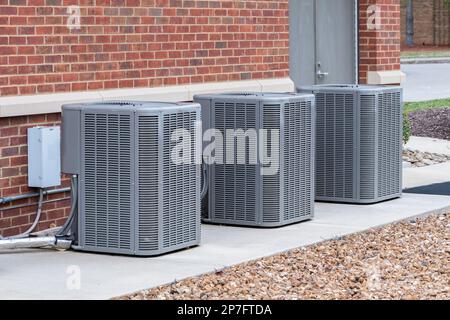 Horizontal shot of commercial air conditioners outside near a maintenance door. Stock Photo
