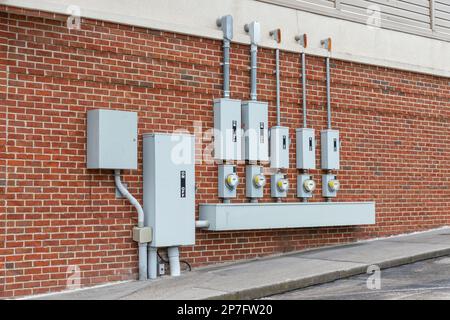 Horizontal shot of electric meters and breakers on the end of a retail strip center brick wall. Stock Photo