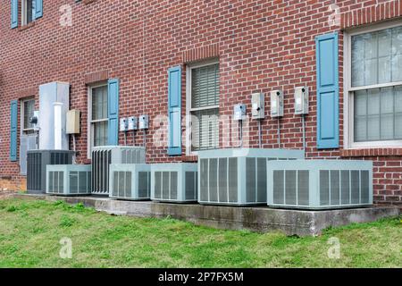 Horizontal shot of a row of various air conditioners attached to multiple businesses in a strip shopping center. Stock Photo