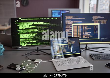 Background image of computers and laptops with green code lines on screen at workplace in IT development company Stock Photo