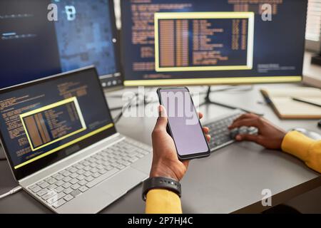 Close up of unrecognizable black man holding smartphone and writing code in IT development company, copy space Stock Photo