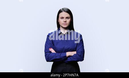 Serious young woman with crossed arms posing over white background Stock Photo