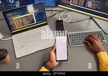 Top view at unrecognizable black man holding smartphone mockup and writing code in IT development company Stock Photo