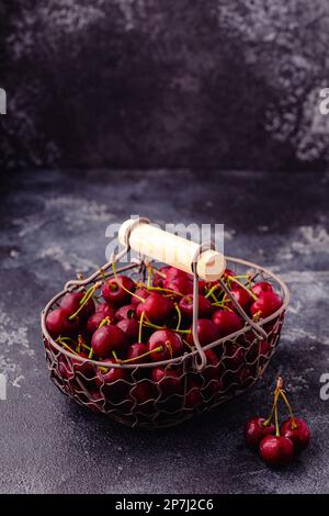 Fresh sweet red cherries in the basket on dark background, selective focus Stock Photo