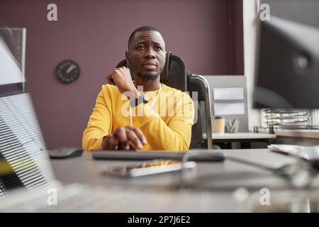 Low angle portrait of focused black man using computer in IT development office, copy space Stock Photo