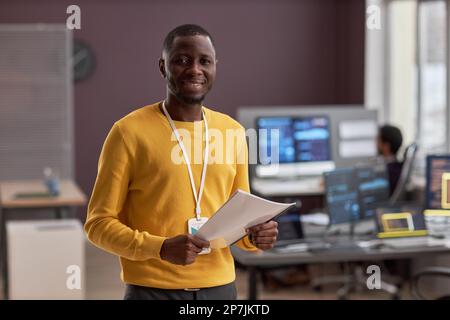 Waist up portrait of smiling black man as IT engineer standing in office, copy space Stock Photo