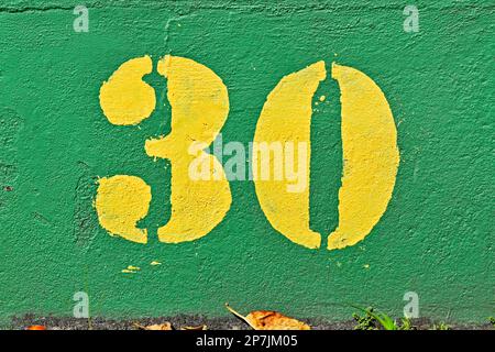 Number 30 painted in yellow on a green wall Stock Photo