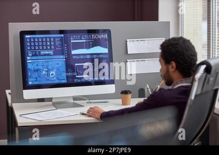 Back view at male IT engineer working with data on computer screen at workplace, copy space Stock Photo