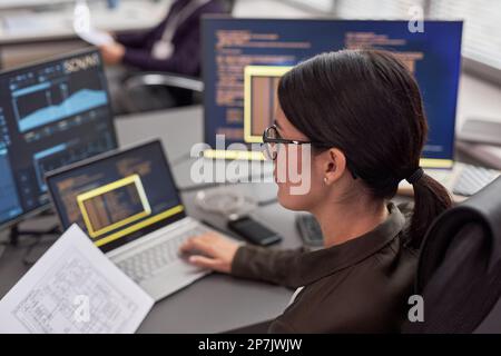 Side view portrait of woman as female IT engineer working with data at desk Stock Photo