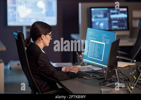 Side view portrait of female IT developer using computer at workplace in high tech office Stock Photo
