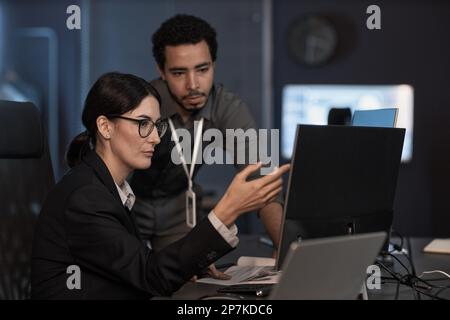 Portrait of senior project manager pointing at computer screen while reviewing code in office Stock Photo